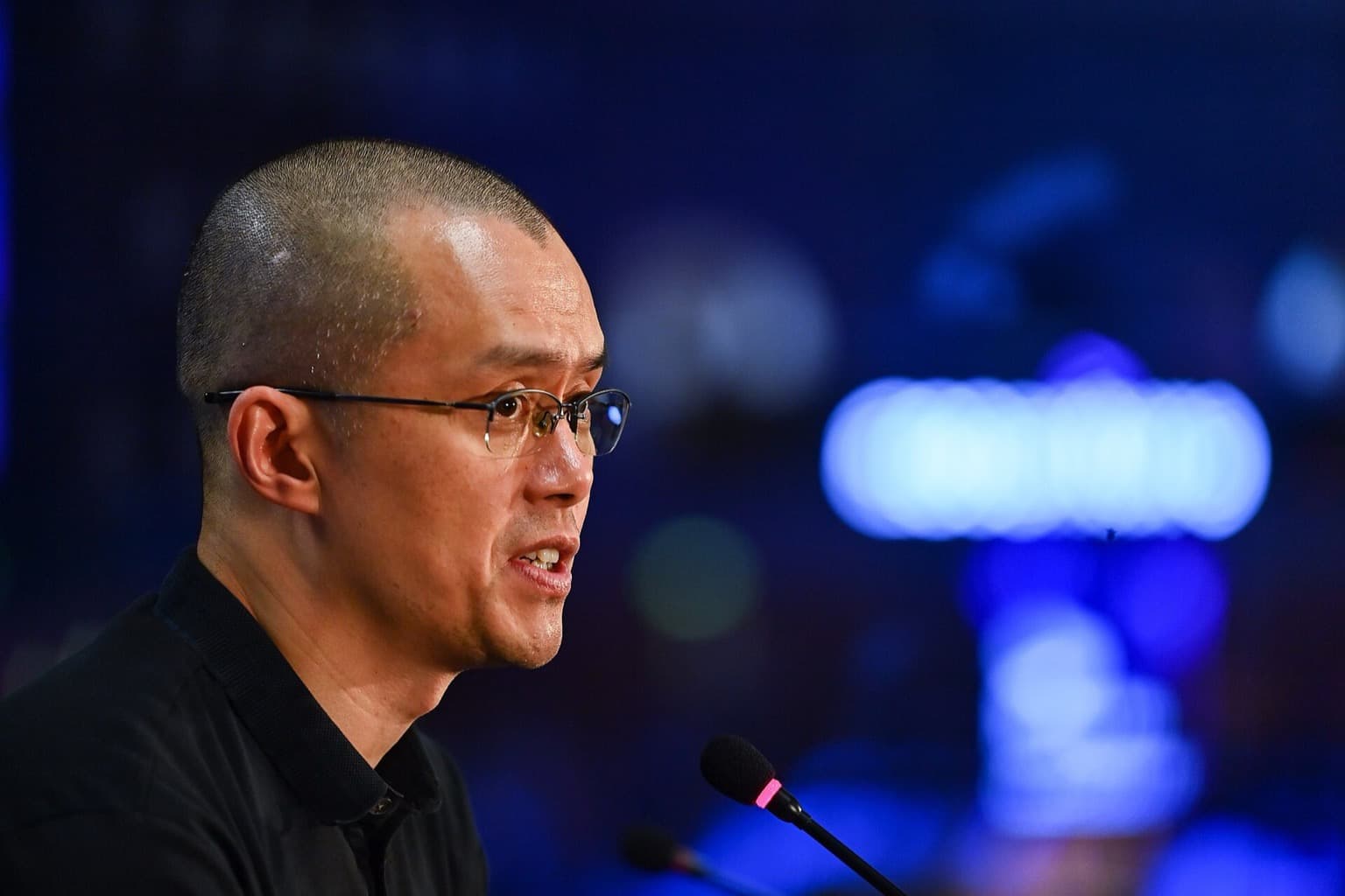 Binance founder Changpeng Zhao speaking into a microphone at a Web Summit press conference.